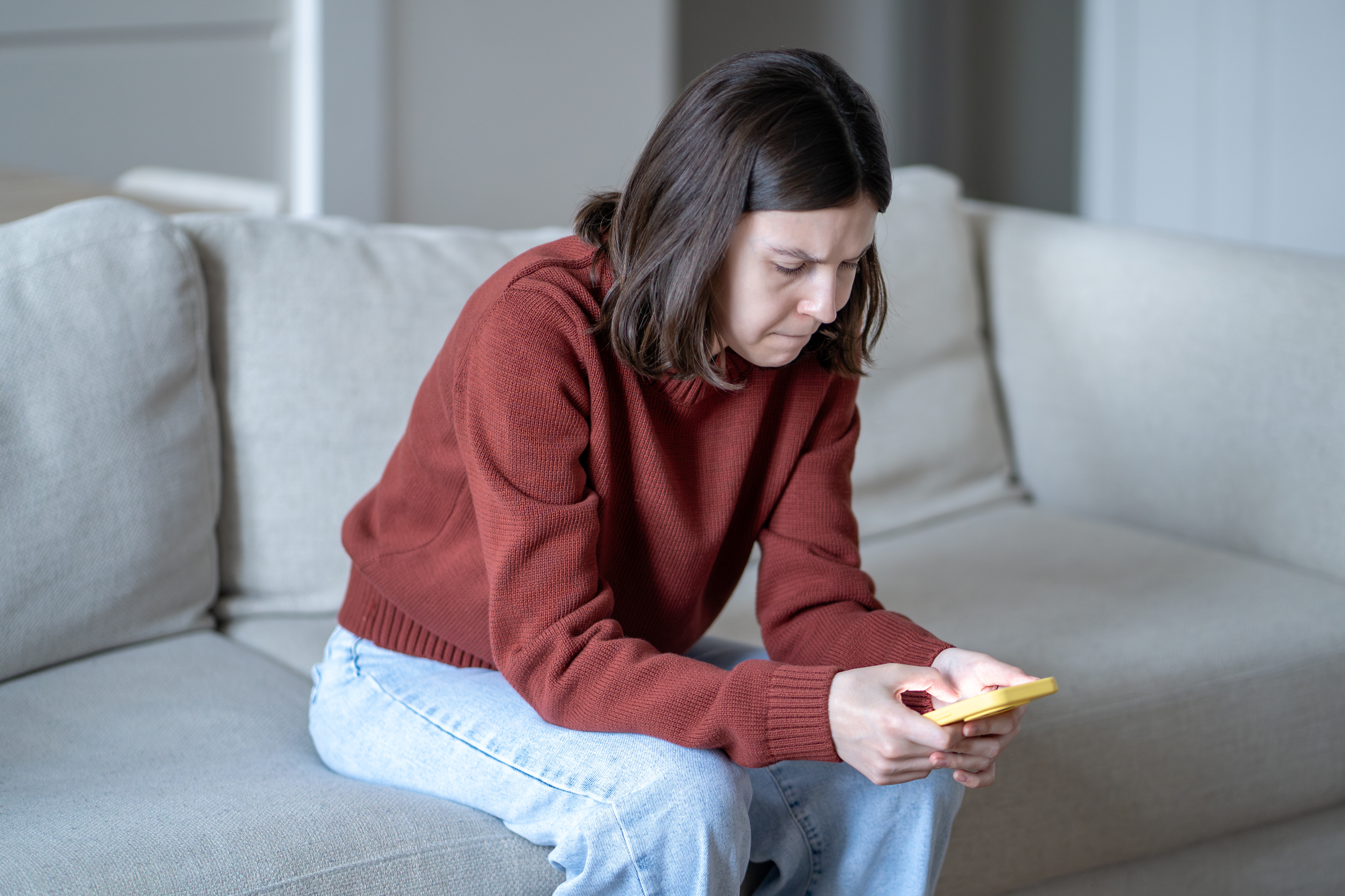 Woman scrolling through social media on her phone with a concerned expression