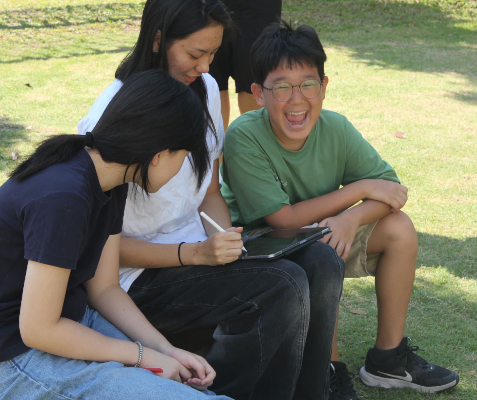 WeLearn learners laughing together outdoors on the grass.