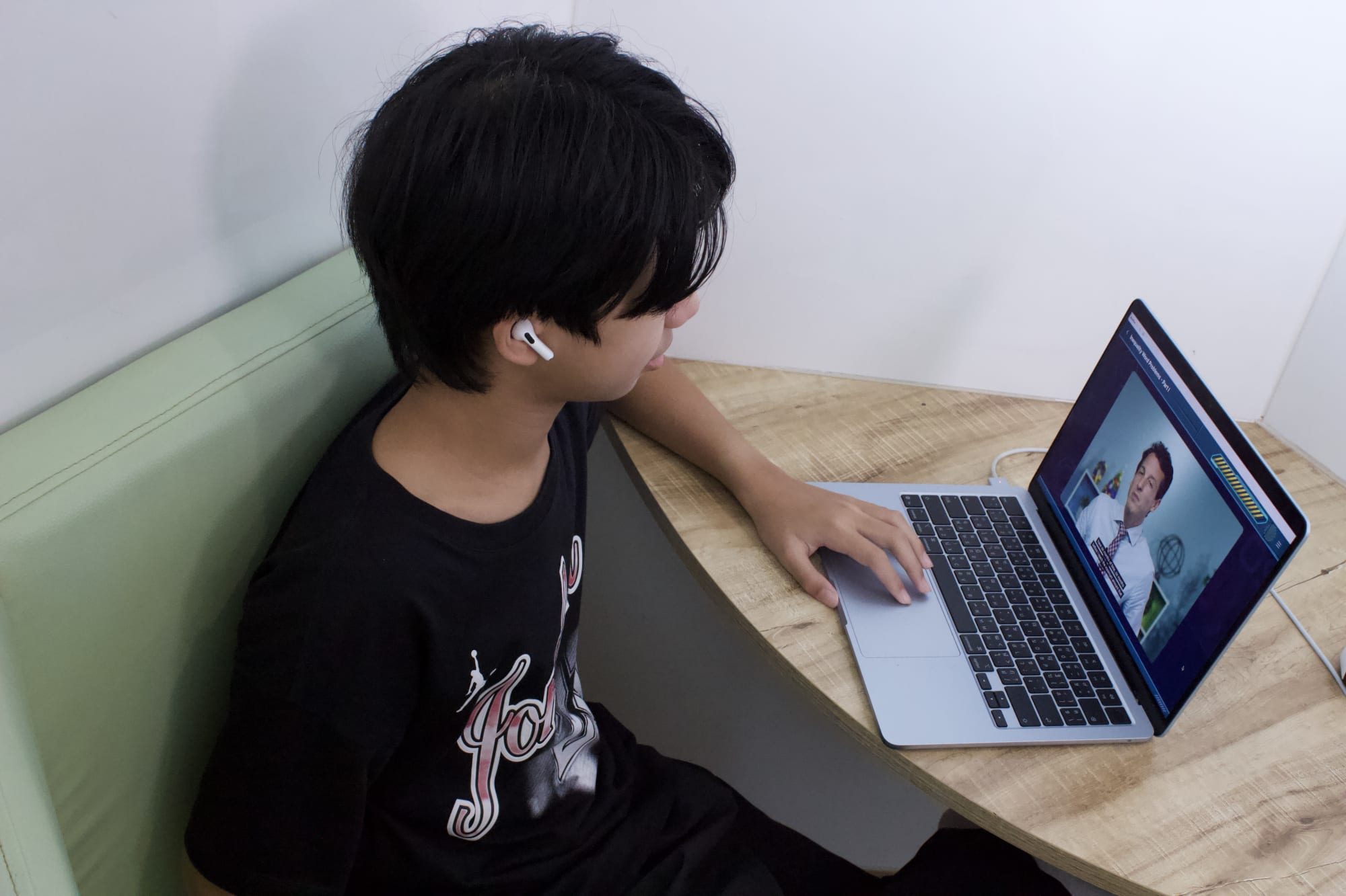 A WeLearn learner working alone on a laptop with earphones in
