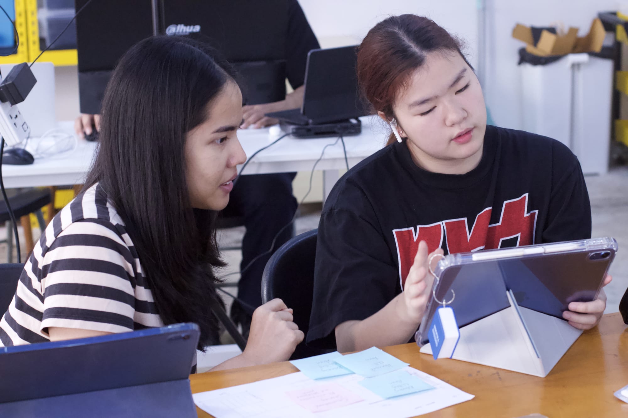 Two WeLearn learners talking through a plan with a tablet and sticky notes