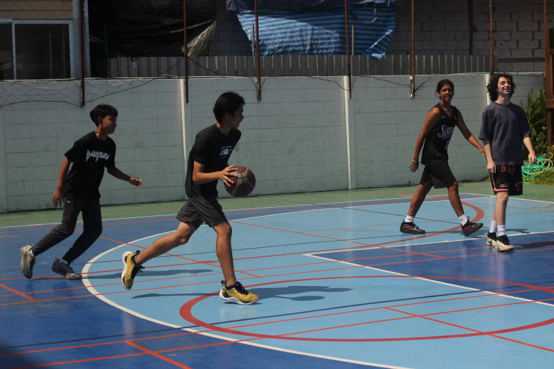 WeLearn learners playing basketball on the court.