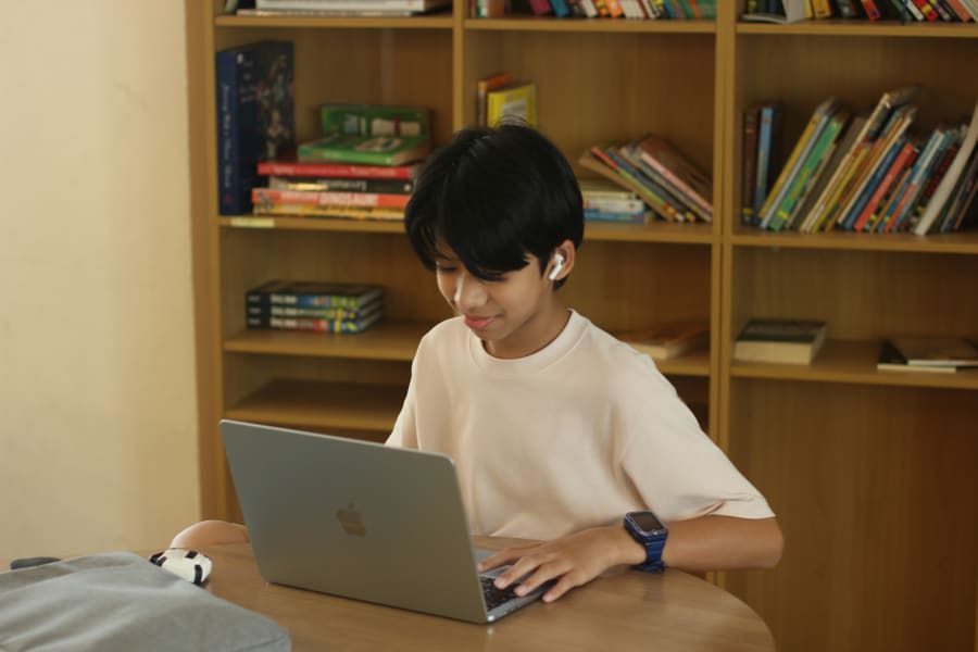 A learner reading quietly beside the library shelves.