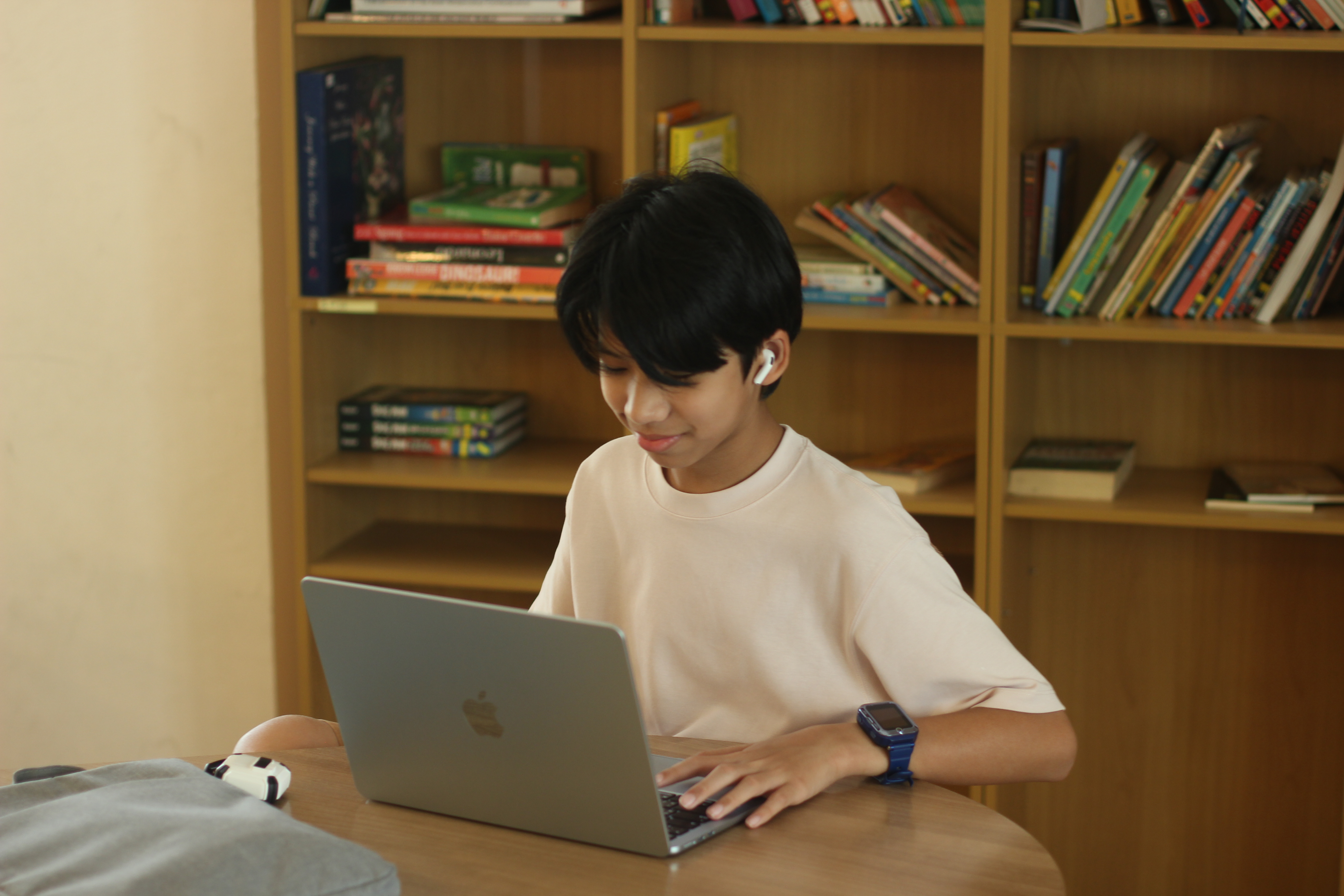 A WeLearn learner working on a laptop in front of the library shelves