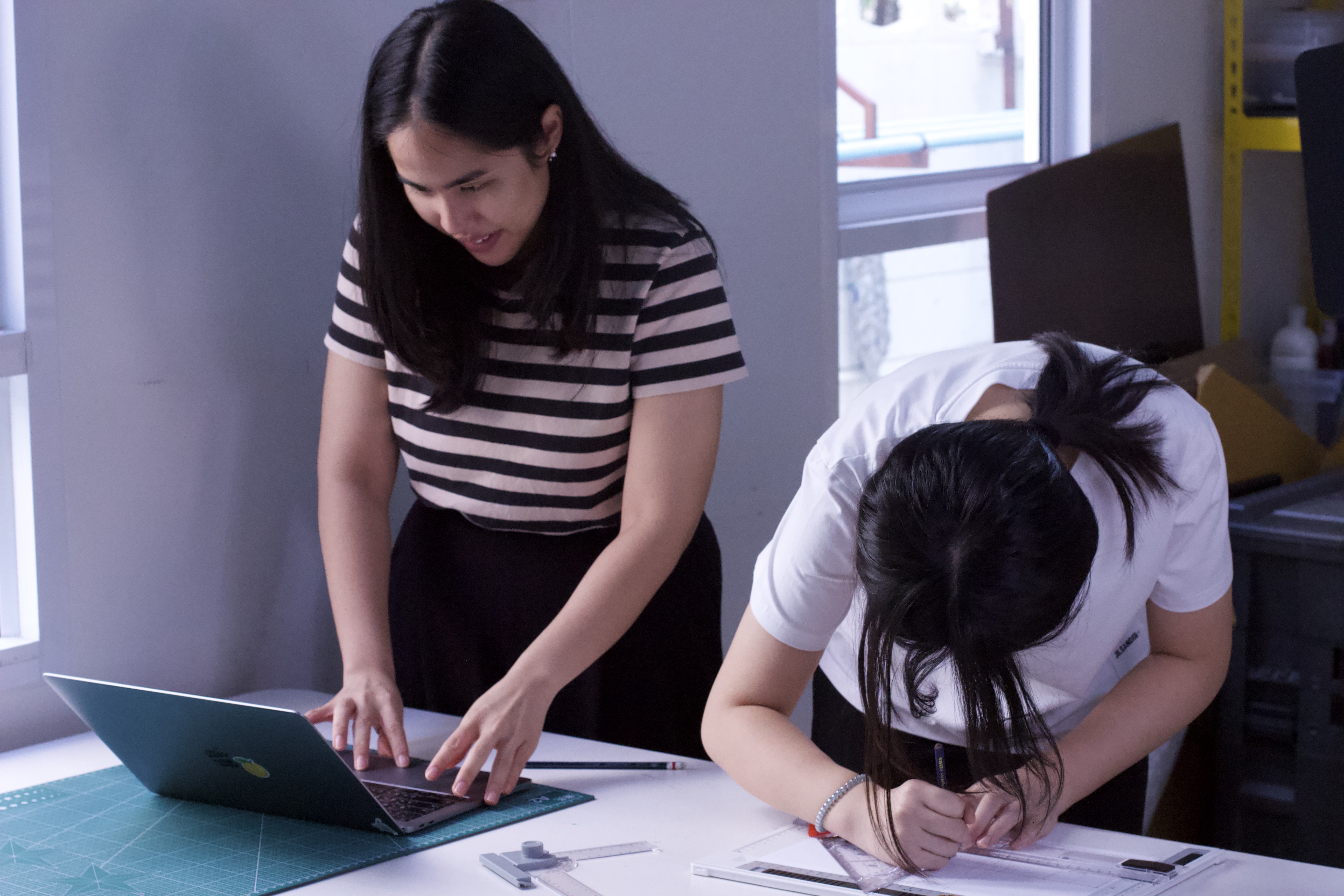 A WeLearn coach leaning in to help a learner at their desk