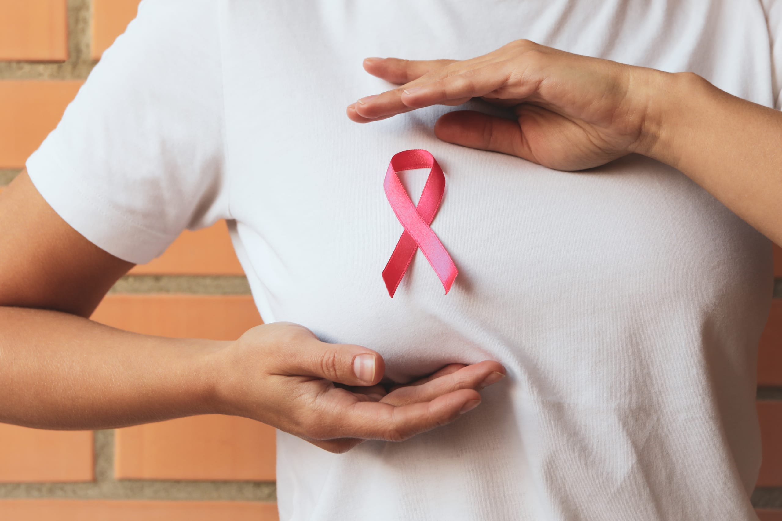 Woman with pink awareness ribbon against brick wall background