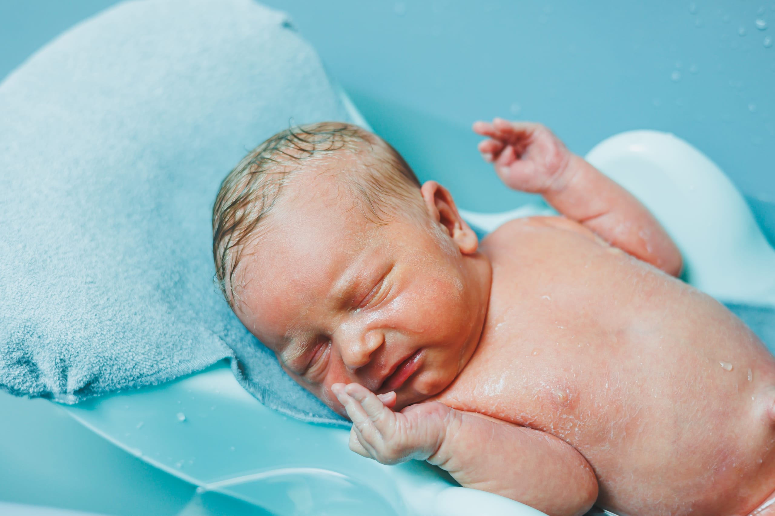 A newborn baby lies in a bathtub, the first bathing of a newborn baby. Bathing a newborn baby.