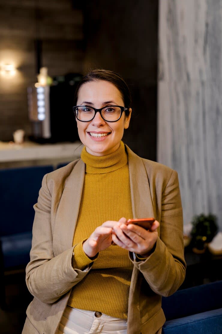 Smiling woman holding a smartphone in a modern lounge