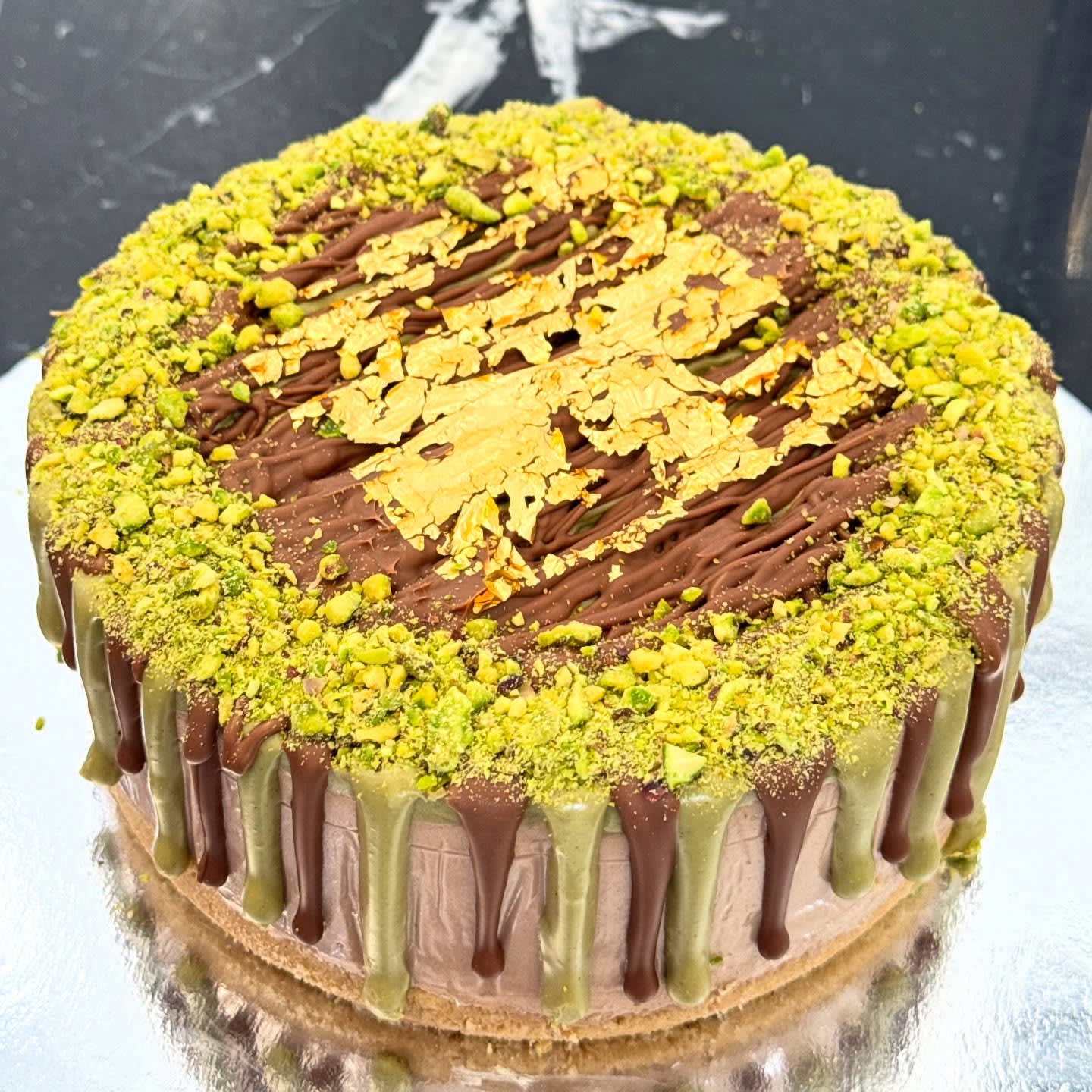 Whole pistachio cheesecake topped with crushed pistachios, shot from overhead.