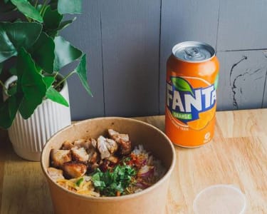 Rice bowl served with spring rolls or dim sims and a can of drink.