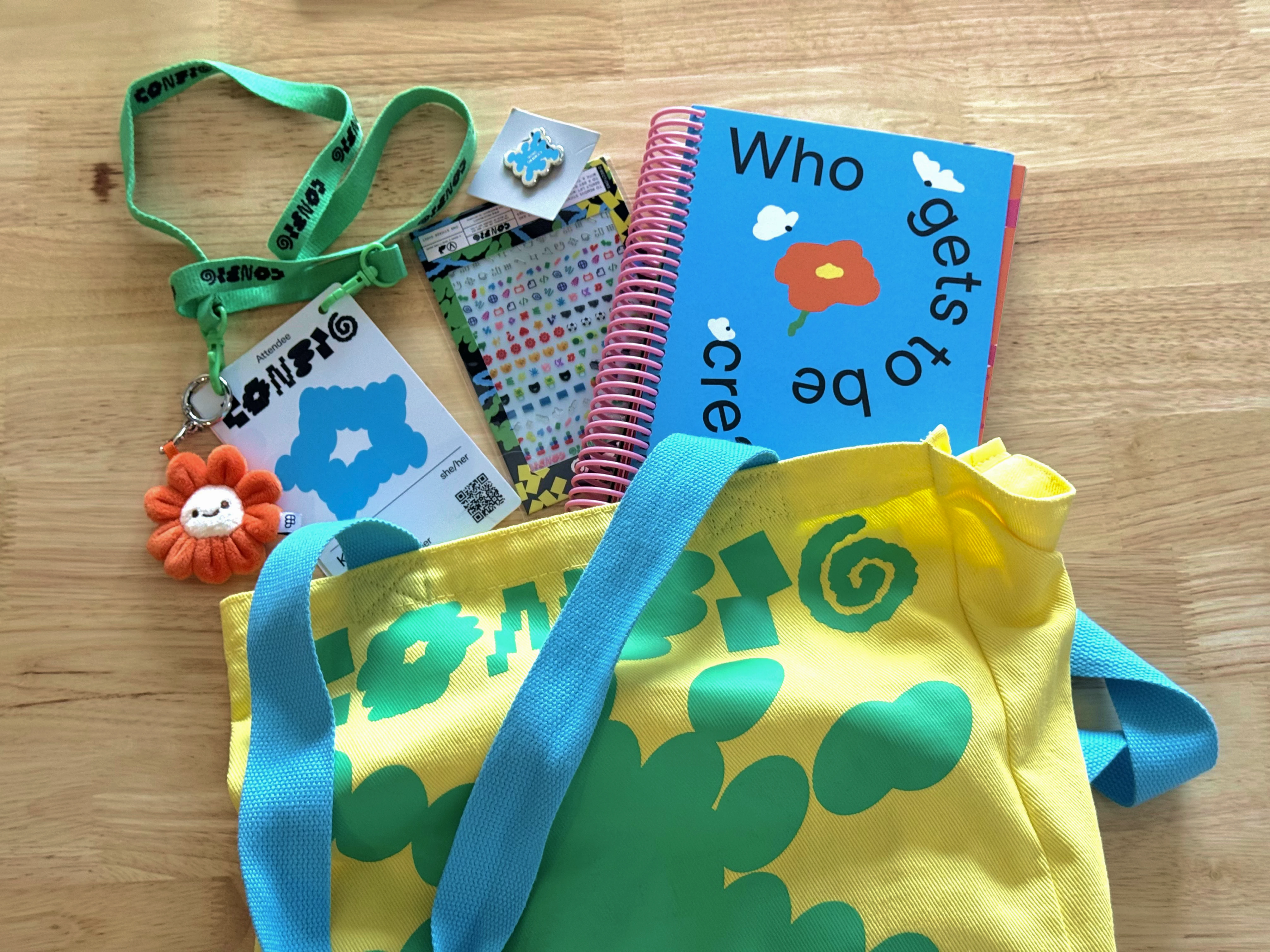 Config 2026 attendee merch, including a lanyard, badge, stickers, notebook, and tote bag