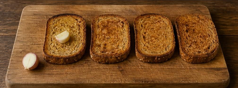 Spanischer Sardinen-Toast auf Tomate und Vollkornbrot – Zubereitung Schritt für Schritt – Brot mit Knoblauch einreiben