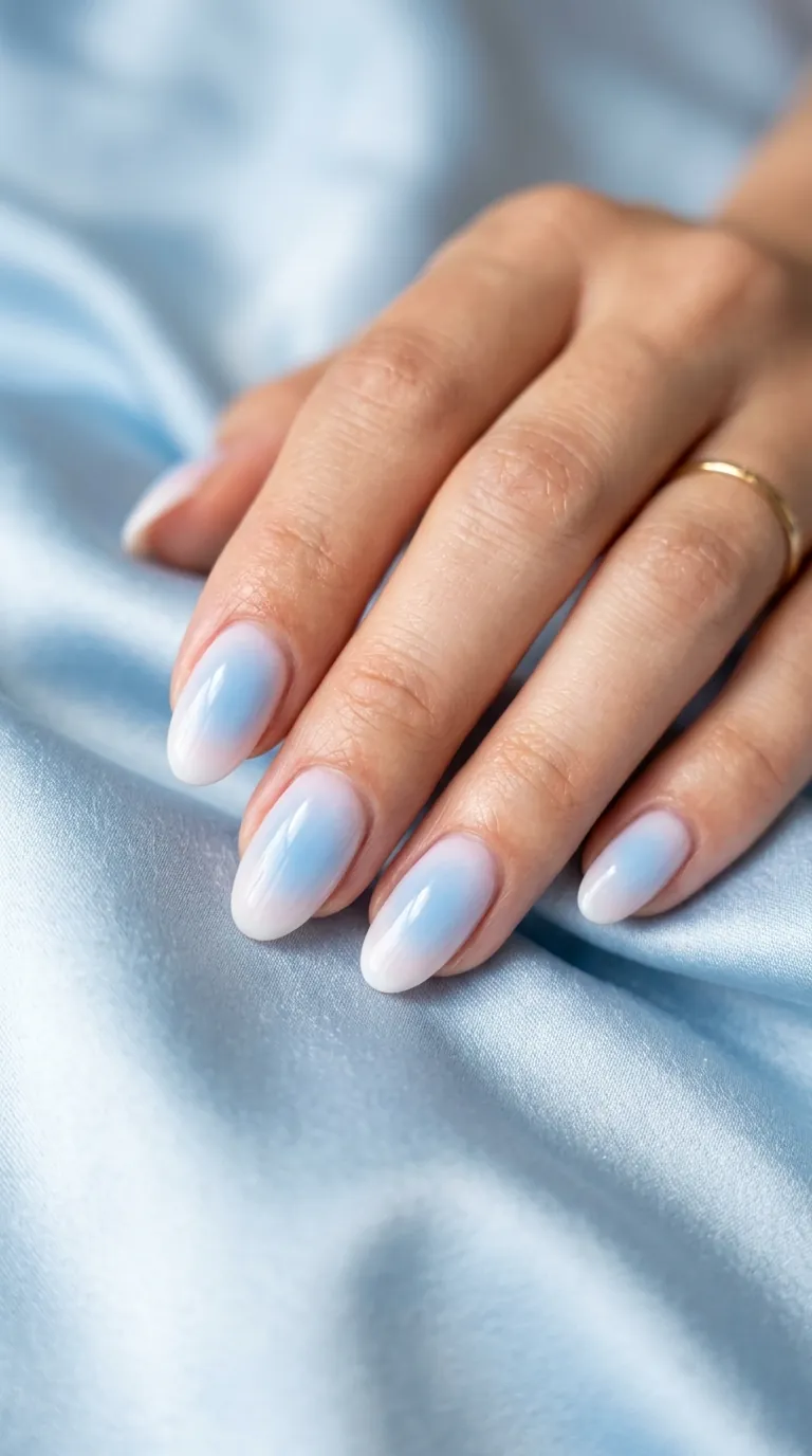 Baby blue aura nails for spring 2026 showing a soft gradient that fades from sky blue in the center to white at the edges on oval-shaped nails Baby blue aura nails for spring 2026 showing a soft gradient that fades from sky blue in the center to white at the edges on oval-shaped nails