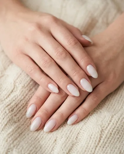 Both hands with medium-length almond nails in a translucent milky white jelly finish, fingers gently overlapping on a cream fabric background Both hands with medium-length almond nails in a translucent milky white jelly finish, fingers gently overlapping on a cream fabric background