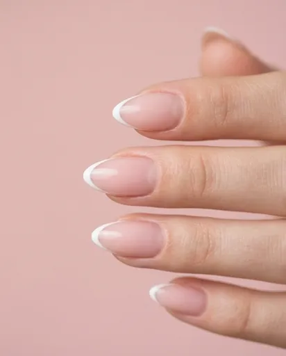 Extreme close-up of almond-shaped nails with a razor-thin white French tip line tracing the edge of the nail, clean cuticles on a soft pink base Extreme close-up of almond-shaped nails with a razor-thin white French tip line tracing the edge of the nail, clean cuticles on a soft pink base
