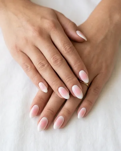 Both hands with almond nails featuring a blush pink aura diffusing from the center of each nail outward into a white border, soft dreamy lighting Both hands with almond nails featuring a blush pink aura diffusing from the center of each nail outward into a white border, soft dreamy lighting