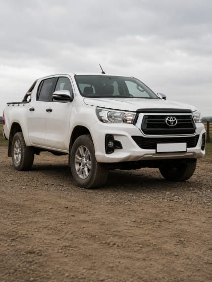 A white Toyota Hilux double-cab bakkie parked on gravel