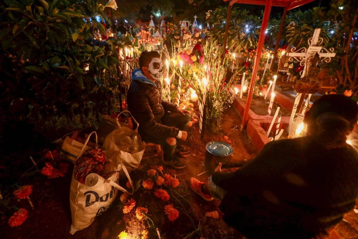 Photo by Carolina Jiménez Mariscal / Cuartoscuro. A man keeping vigil at a grave in an Oaxacan cemetery during Día de Muertos.