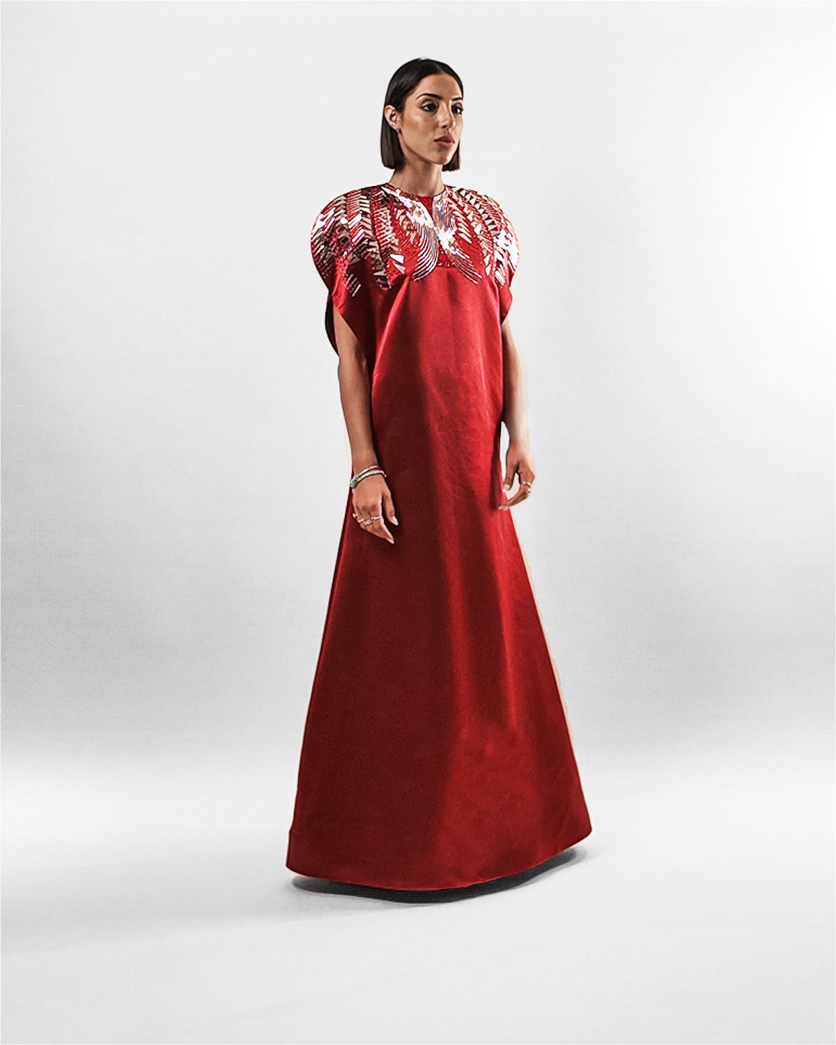 garnet silk gown Tanisha Rada model wearing the in Garnet silk gown, featuring statement shoulders and embellished neckline. side view.