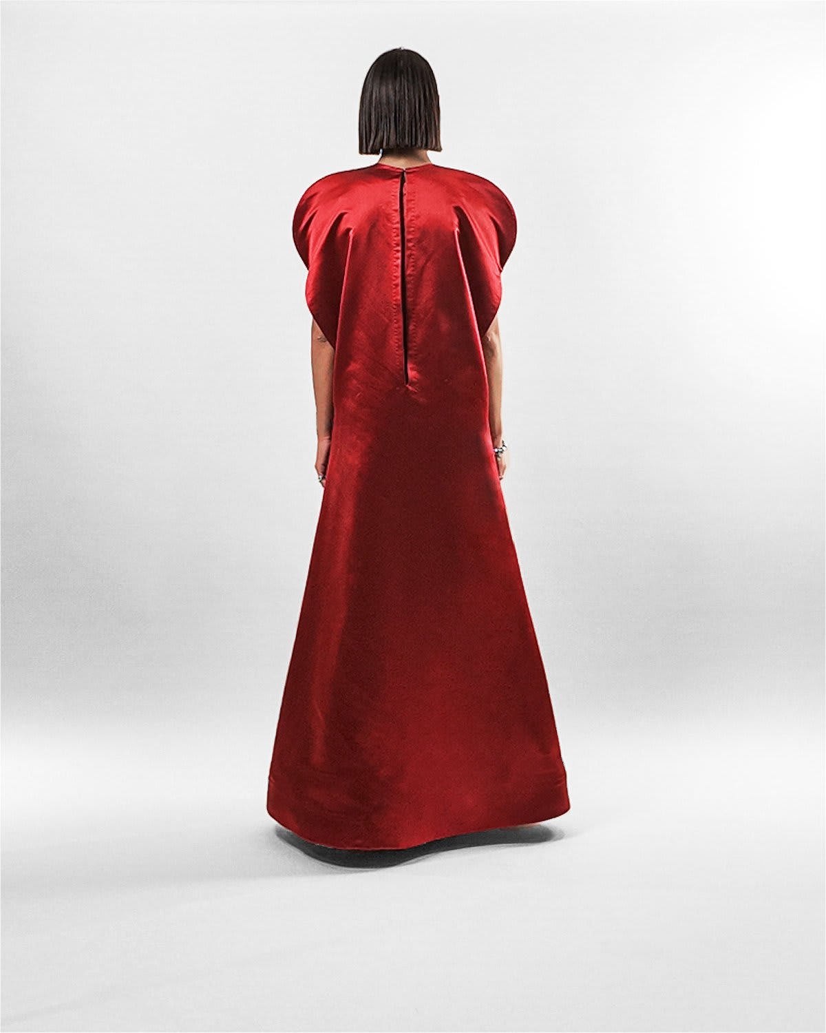 garnet silk gown Tanisha Rada model wearing the in Garnet silk gown, featuring statement shoulders and embellished neckline. back view.