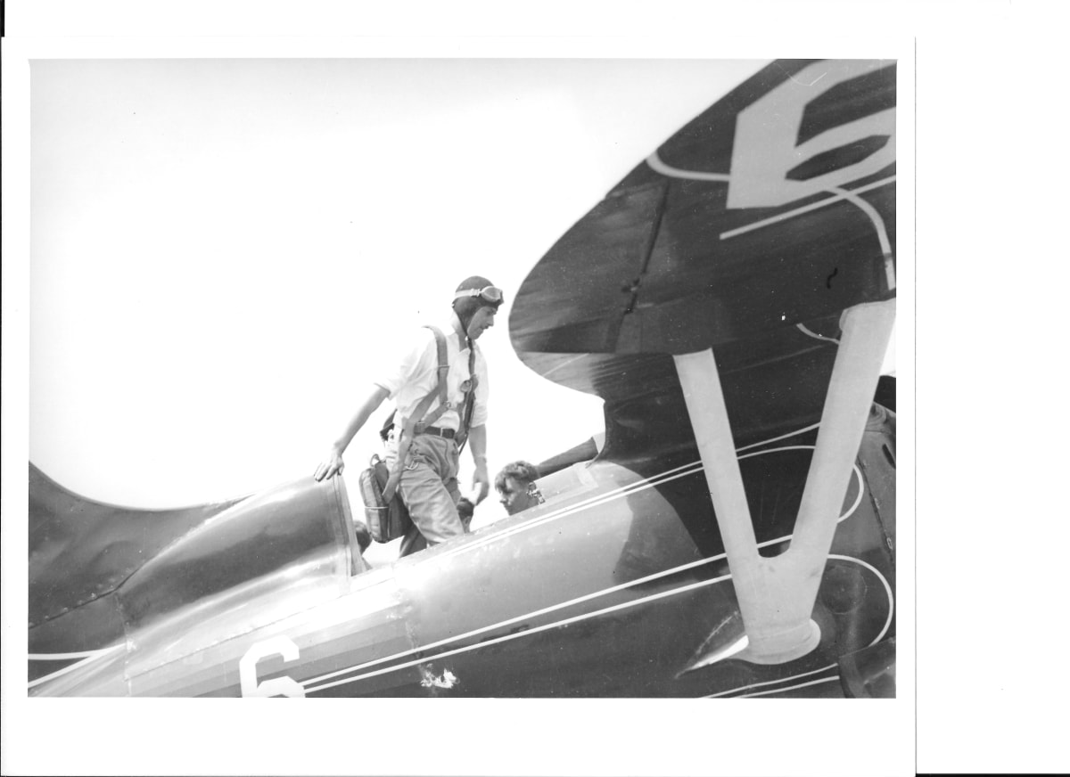 Bob Hall standing in Hall Bulldog cockpit with parachute