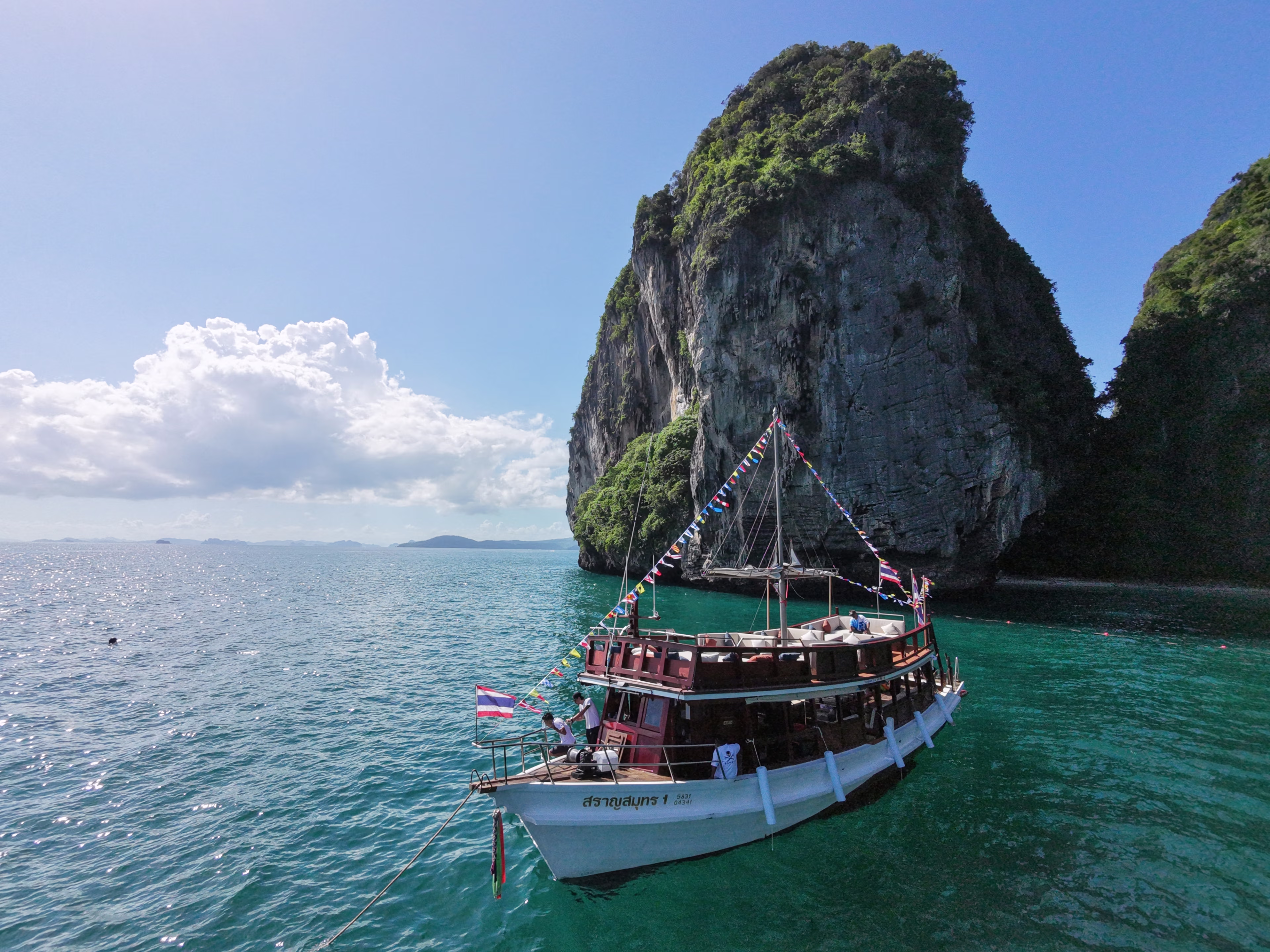 Bamboo Sunset Cruise anchored beneath a limestone cliff in Krabi