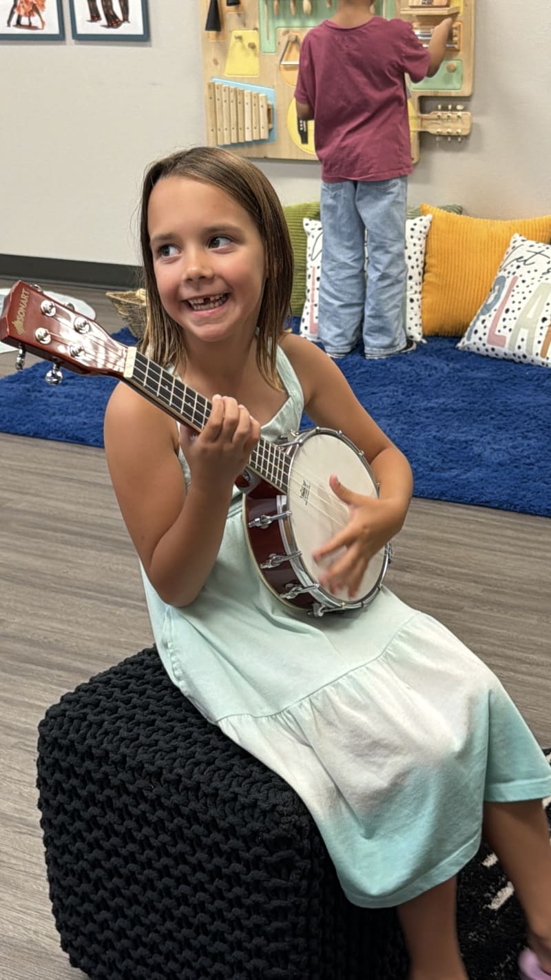 A child playing a banjo in the music room during project time