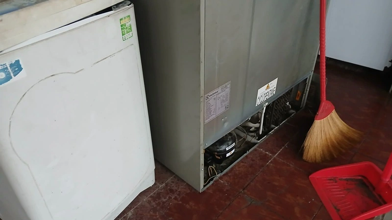 Kỹ thuật viên kiểm tra block phía sau tủ lạnh cũ trước khi thu mua tại Bình Thạnh