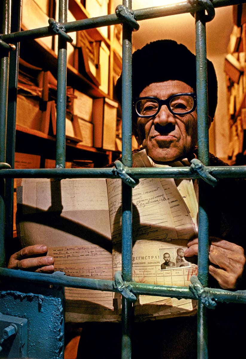 Asir Sandler, in the entrance to his old cell in Magadan prison, holding his original arrest papers, file no. 2-5469, from...