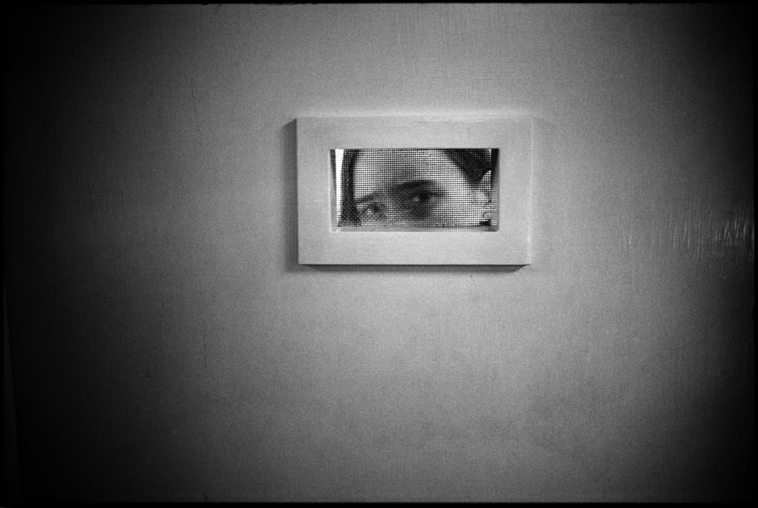 Tommie peeking out of room window, Ward 81, Oregon State Hospital, Salem, Oregon, USA, 1976