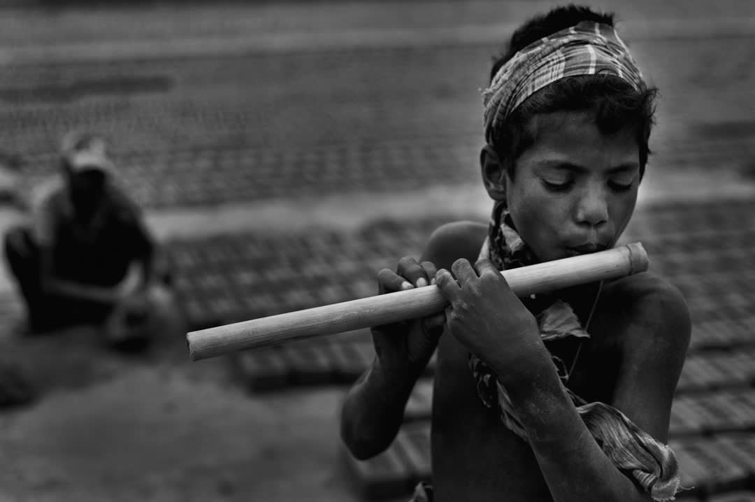 Shafik (11) plays his village flute during breaks. Brickfield life didn’t silence his music. Bakkar brickfield, Chittagong...