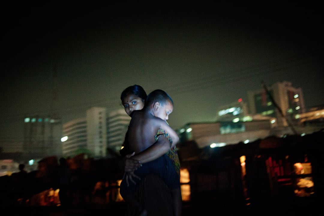 Bangladesh, Dhaka. Golape, 22 years old, is pictured at night with her son in the Kawran Bazar slum. She is a climate migr...