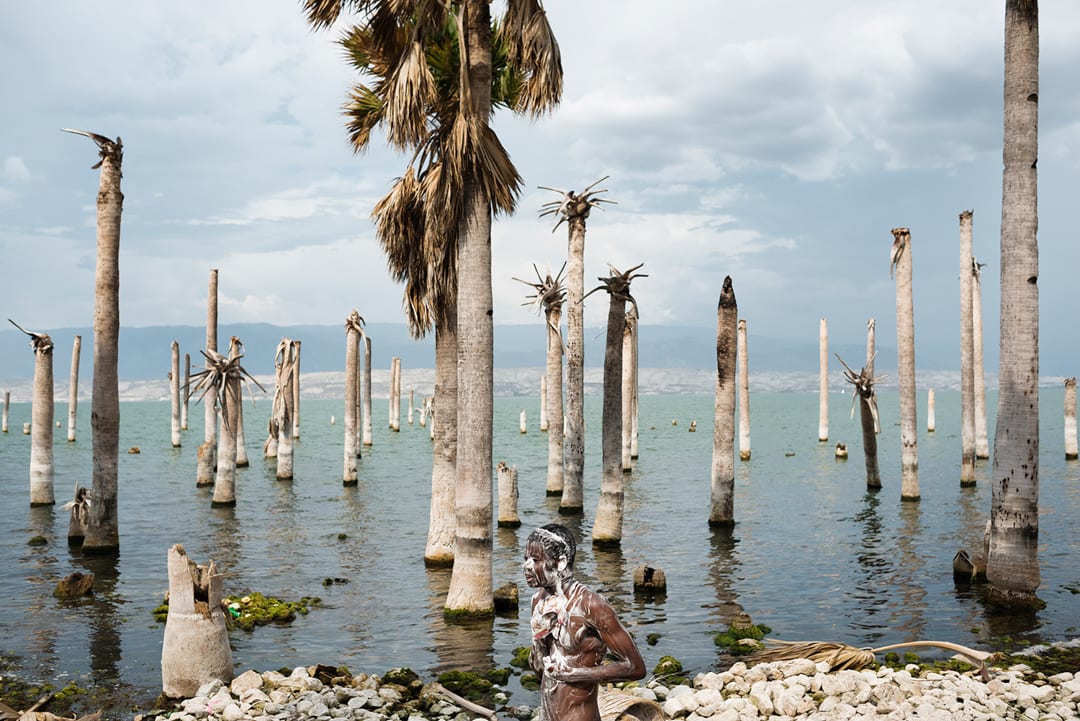 Lake Azuéi, Haiti. A young man washes on the shore of Lake Azuéi. Trunks of dead palm trees remain after the passage of a ...