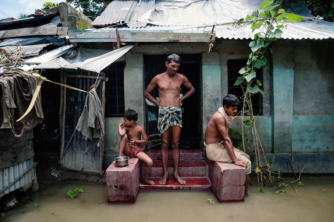 Bangladesh, Satkhira district. Mr. Anisuzzaman stands outside his home in Debnagar. The river has flooded its banks for th...