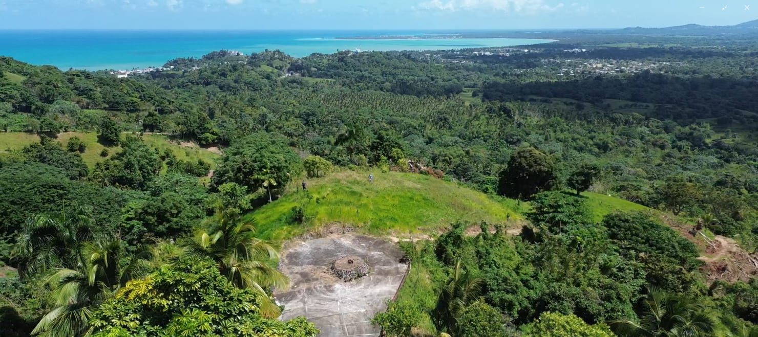 Drone view of the Vista Serena hillside lots descending toward the turquoise coast — FAQ on land, titles, and pricing