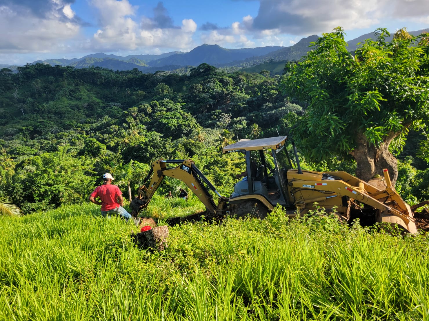 Chantier réel sur la crête du domaine Vista Serena Miches — engin de terrassement et ouvrier, montagnes en arrière-plan