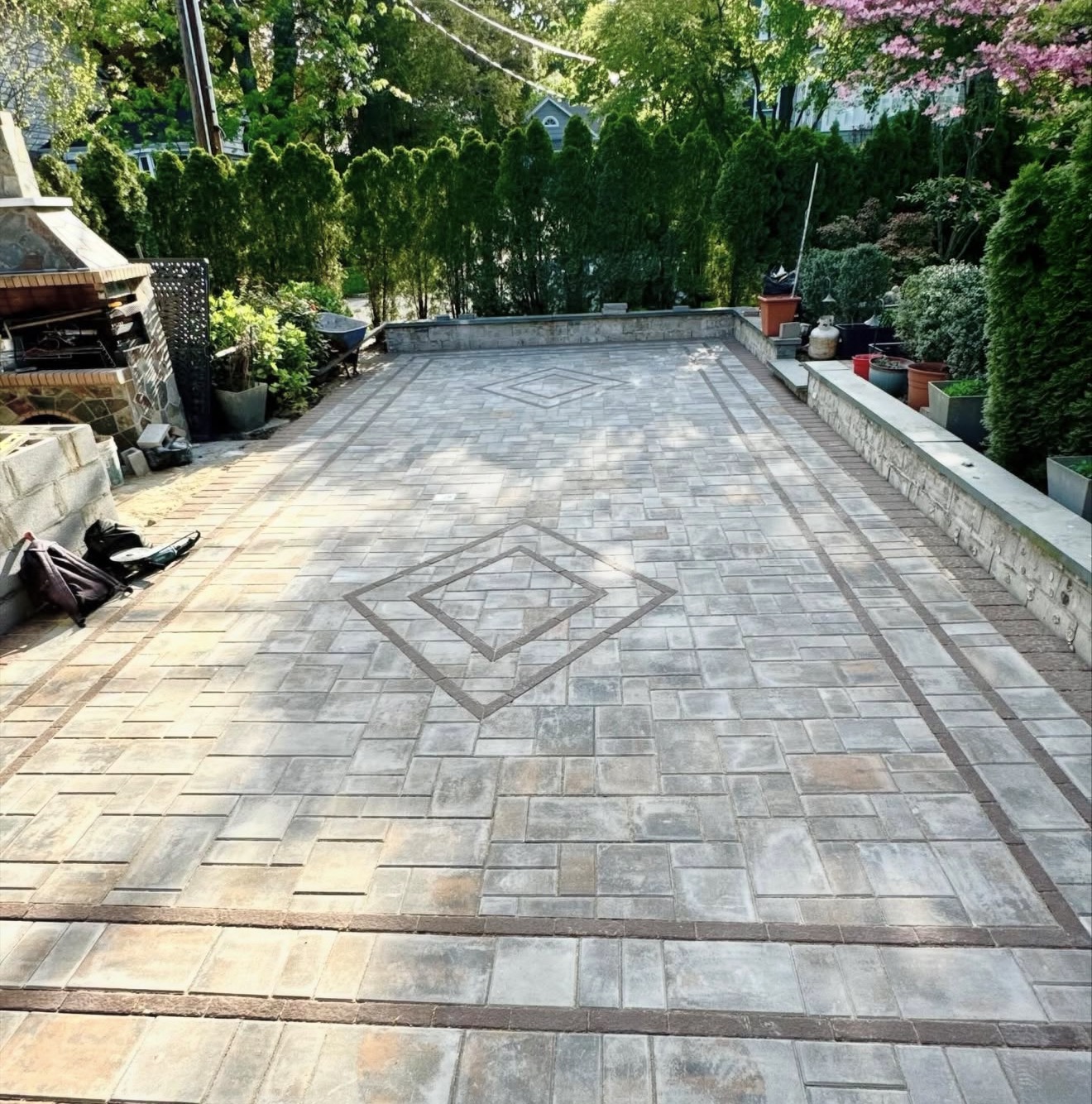 Diamond pattern paver patio with stone retaining wall by Fibinachi Construction