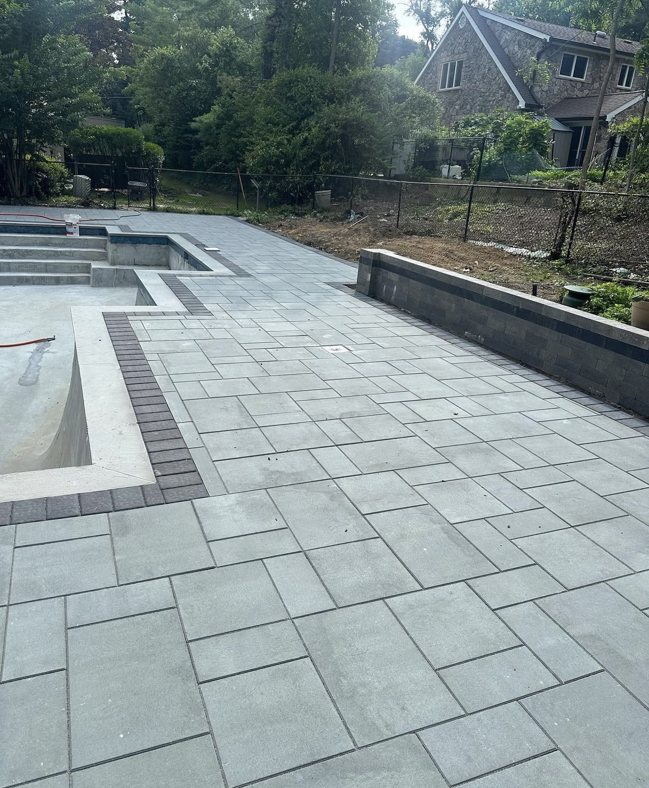 Pool paver surround with retaining wall by Fibinachi Construction Long Island