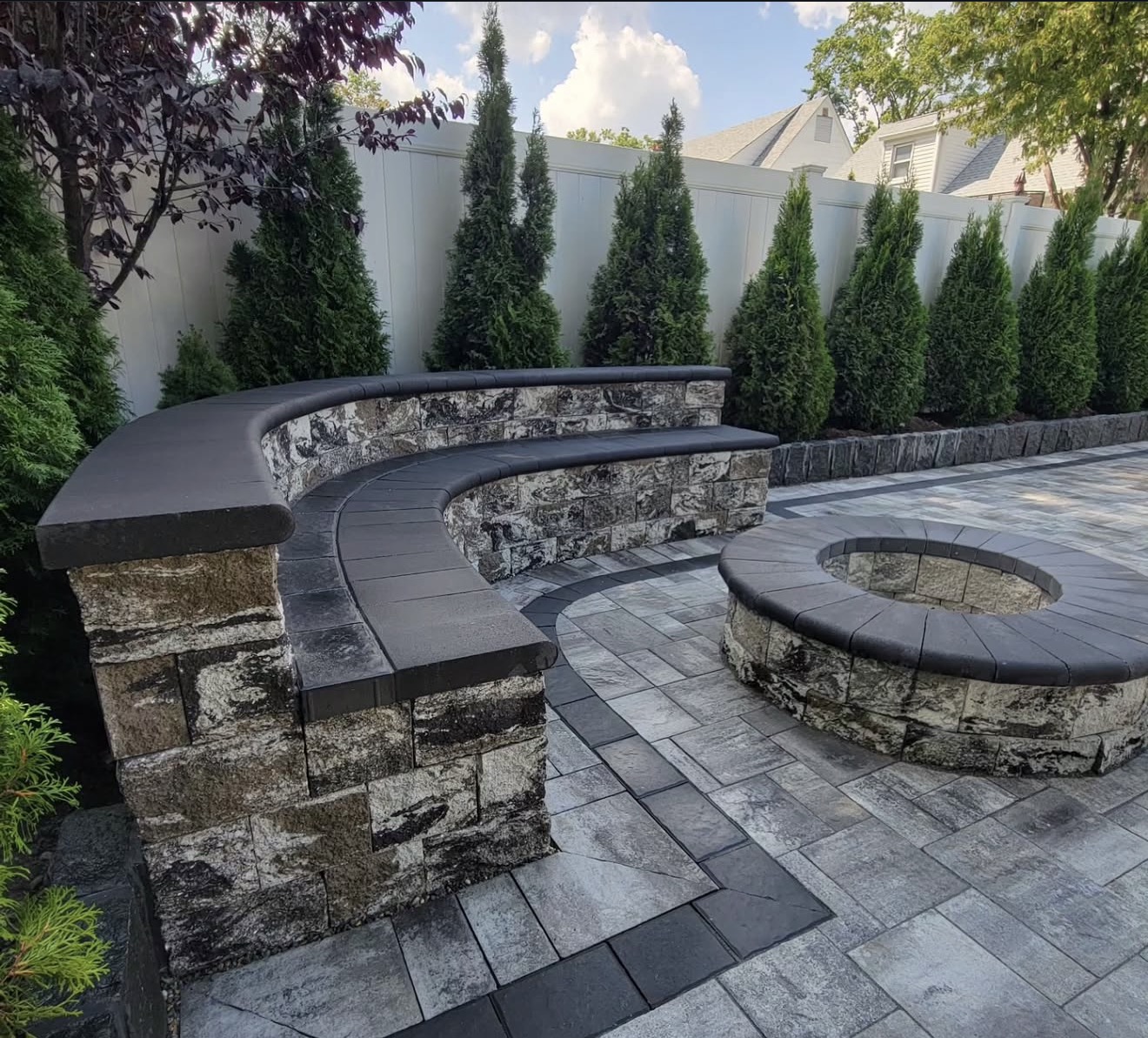 Stone curved seating wall with fire pit and pavers by Fibinachi Construction