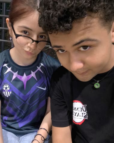 Katheryn con camiseta de futbol morada y Brandon con camiseta negra, sentados juntos
