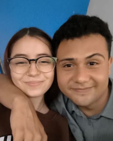 Katheryn y Brandon sonriendo a la camara, ella con sudadera y el brazo de el sobre su hombro