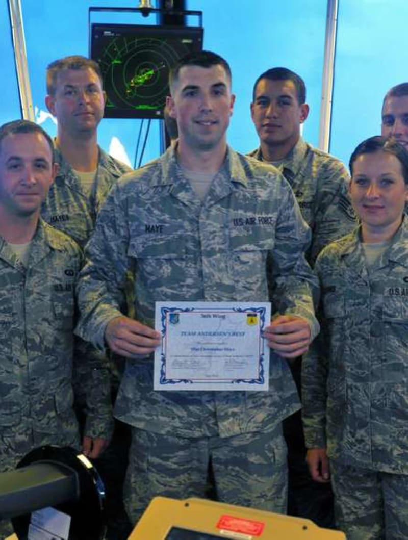 Chris Maye holding a certificate alongside fellow airmen.