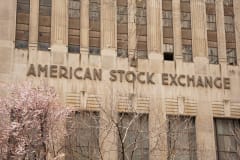 Facade of the American Stock Exchange Building in New York City during spring with blooming trees.