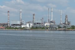 A large oil refinery complex next to the water with cloudy skies.