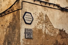 Street signs on a rustic wall in the medina of Fes, Morocco, showcasing cultural heritage.