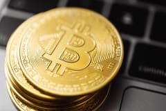 Close-up image of Bitcoin coins stacked on a laptop keyboard, symbolizing digital currency and blockchain technology.