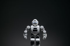 Close-up of a white toy robot with glowing eyes in a studio setting.