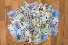 Aerial view of mixed Euro and US Dollar banknotes on a wooden floor, symbolizing global finance.