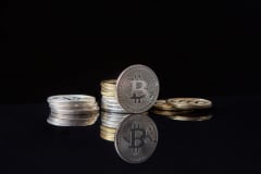 Silver bitcoins stacked on a reflective surface with a dark background, symbolizing cryptocurrency and digital wealth.