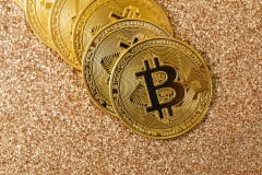 Golden Bitcoin coins arranged on a sparkling glitter surface, symbolizing cryptocurrency and wealth.