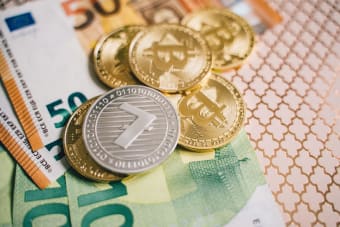 Close-up of digital cryptocurrency coins and Euro banknotes, representing modern finance.